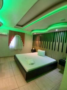 a bedroom with a large bed with green lights at Motel Encontros in Poá +8 photos