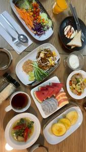 a wooden table with plates of food on it at Bed By City Hotel in Bangkok