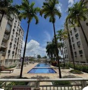 una piscina con palme di fronte agli edifici di Apartamento para COP30 15 min do Hangar Próximo ao aeroporto Belém a Belém