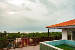 een balkon met een zwembad en een huis bij Hotel Anandam Elegance in Morjim