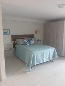 a bedroom with a bed with a blue comforter at Flat beiramar praia de Tabatinga in Conde
