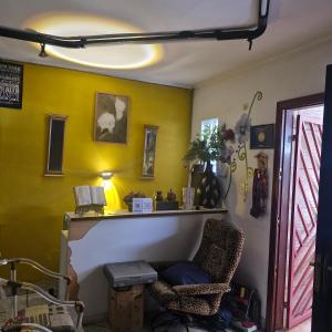 Zimmer mit einem Stuhl und einer gelben Wand in der Unterkunft Residencia familiar in São Paulo