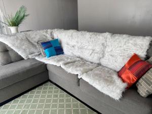 a white blanket on a couch with three pillows at Modern Lux 3BR King Bed in Copperas Cove