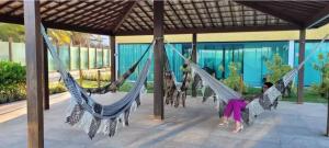 a rendering of two people in hammocks in a pavilion at Flat beiramar praia de Tabatinga in Conde