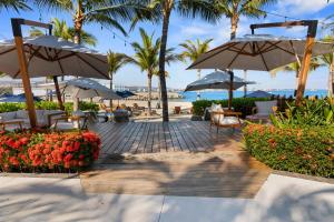 a patio with tables and umbrellas on the beach at Peaceful Retreat with Pool – Ideal for Relaxation in Cruz de Huanacaxtle