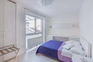 a white bedroom with a bed and a window at SWEETHOME TALVERA - con Garage in Bolzano