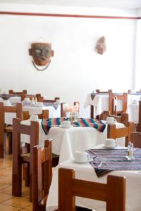 um restaurante com mesas e cadeiras com uma máscara na parede em Hotel Maya Palenque em Palenque