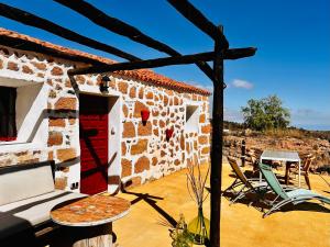 a building with a red door and chairs on a patio at Las Casitas - Casa Higo with shared Jacuzzi in Granadilla de Abona