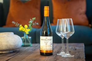 a bottle of wine sitting next to two wine glasses at Stylish cosy retreat with private parking in Penryn +17 photos