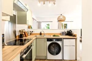 a kitchen with a washing machine and a sink at Stylish cosy retreat with private parking in Penryn