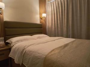 a bedroom with a white bed with a green headboard at Casa Thea Cebu in Talisay