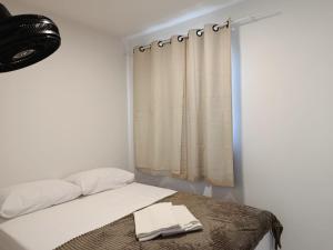 ein Schlafzimmer mit einem Bett mit einem Vorhang und einem Fenster in der Unterkunft Apê econômico a 4 km de Muro Alto in Ipojuca