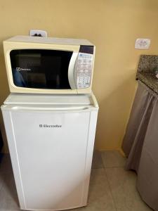 a microwave sitting on top of a refrigerator at Mini Casa 5 in Itajaí