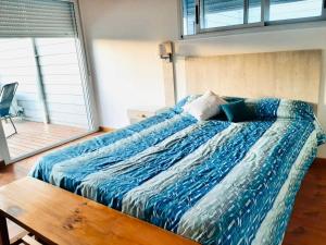 ein Bett mit blauer Decke in einem Schlafzimmer in der Unterkunft Casa Blanca MH in Monte Hermoso + 3 Fotos