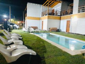 eine Reihe von weißen Liegestühlen neben einem Pool in der Unterkunft Casa Blanca MH in Monte Hermoso