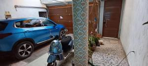 a blue car parked next to a house with a scooter at Casa San Ramón in San Ramón