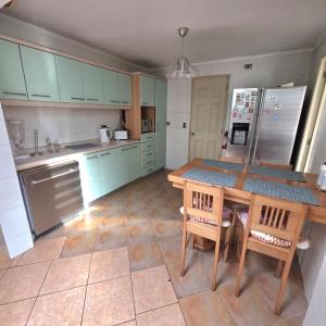 a kitchen with blue cabinets and a table with chairs at Acogedora Casa con Tinaja y Jacuzzi y RENT A CAR in Puerto Varas