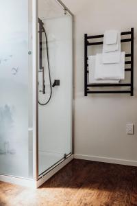 a shower with a glass door with a bed at The Lilly Pad - Hokitika in Ruatapu