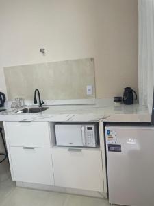 a white kitchen with a sink and a microwave at Apartamento em Sinop 10 in Sinop