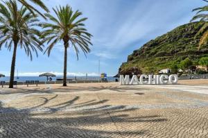 een strand met palmbomen en het bord voor machico bij Machico Bay in Machico