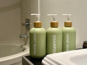 Modern 3-Bedroom Apartment in UBC في فانكوفر: زجاجتان خضراوان موضوعتان أعلى حوض الحمام +25 صورة