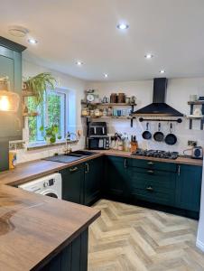 une cuisine avec des armoires vertes et une cuisinière four supérieur dans l'établissement Stylish home, 3 bed with garden, Fast WiFi Parking, à Peterborough