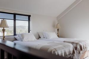 a white bedroom with two beds and a window at The Black Barn - Panoramic, Private & Luxury in Marsden