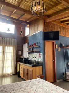 a kitchen with wooden walls and a chandelier at Chalé Alecrim in Córrego do Bom Jesus +15 photos