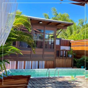 a house with a swimming pool in front of it at Chalés Mãe Natureza - Reserva do Matuto in Vera Cruz de Itaparica