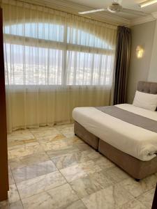 a bedroom with a bed and a large window at البرق للشقق المفروشة in Salalah