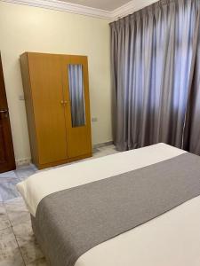 a bedroom with a bed and a wooden cabinet at البرق للشقق المفروشة in Salalah