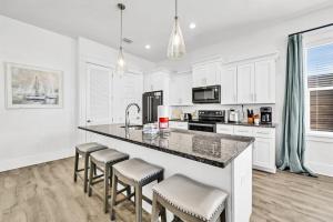 una cucina con armadi bianchi e una grande isola con sgabelli da bar di Emerald Escape in Miramar Beach! Golf Cart, 4BR, 4BA, Sleeps 14, Pool, Beach a Destin