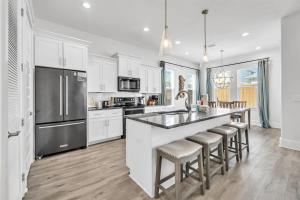 una cucina con armadi bianchi e una grande isola con sgabelli da bar di Emerald Escape in Miramar Beach! Golf Cart, 4BR, 4BA, Sleeps 14, Pool, Beach a Destin