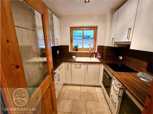 a kitchen with white cabinets and a sink and a window at Ferienwohnung Soiernseelig in Wallgau +72 photos