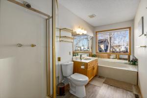 a bathroom with a toilet and a tub and a sink at Acreage, 3 King Beds and Ensuites, Dance Floor, Fireplace, AC in Calgary +17 photos