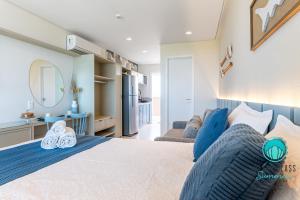 Refúgio Verão - Flat de alto padrão na praia do Cupe - Porto de Galinhas في بورتو دي غالينهاس: غرفة نوم بها سرير كبير وغرفة معيشة