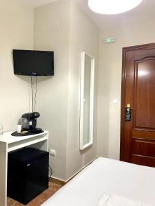a room with a bed and a television on a wall at La Vega Rooms in Huelva +25 photos