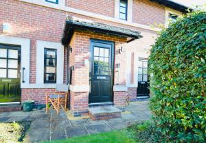 a brick house with a black door and a patio at Luxury Two Bed Suite - Walk To Trentham Gardens! in Stoke on Trent