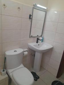 a bathroom with a white toilet and a sink at Tulia homes in Kanga +13 photos