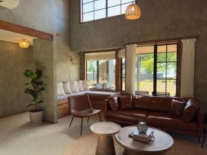 a living room with a leather couch and a window at Stillwater Residence - Lakeview Serenity Retreat in Ngongotaha