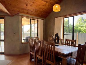a dining room with a table and chairs and windows at Stillwater Residence - Lakeview Serenity Retreat in Ngongotaha