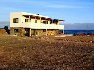a house on the beach with the ocean behind it at Kasa surf in Porto Novo