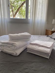 einen Haufen Handtücher auf einem Bett mit Fenster in der Unterkunft Depa MDP- 3 ambientes in Mar del Plata