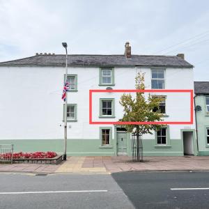 ein weiß-grünes Gebäude mit einem roten Streifen darauf in der Unterkunft Hadrians Retreat, Cosy 1 Bed Flat - near M6 Jct45, A75, Gretna & Carlisle in Longtown