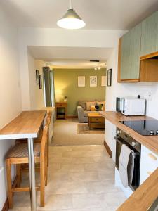 eine Küche und ein Wohnzimmer mit einem Tisch und einer Couch in der Unterkunft Hadrians Retreat, Cosy 1 Bed Flat - near M6 Jct45, A75, Gretna & Carlisle in Longtown