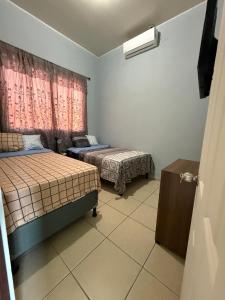 a small room with two beds and a window at Casa en residencial Metrópoli San Gabriel, Nejapa San Salvador in Nejapa