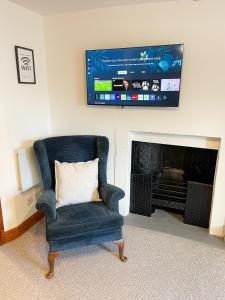 ein Wohnzimmer mit einem Stuhl und einem Flachbild-TV in der Unterkunft Hadrians Retreat, Cosy 1 Bed Flat - near M6 Jct45, A75, Gretna & Carlisle in Longtown