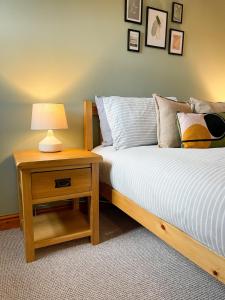 ein Schlafzimmer mit einem Bett und einem Nachttisch mit Lampe in der Unterkunft Hadrians Retreat, Cosy 1 Bed Flat - near M6 Jct45, A75, Gretna & Carlisle in Longtown