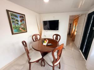 a dining room with a table and chairs and a television at Finca Villa Maju in Papagalleros
