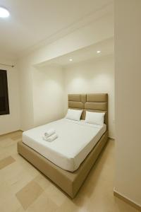 une chambre avec un lit avec des draps blancs et des oreillers dans l'établissement 1CH & Salon,climatiseur-fibre optique-gare TGV 2min de la corniche malabata, à Tanger